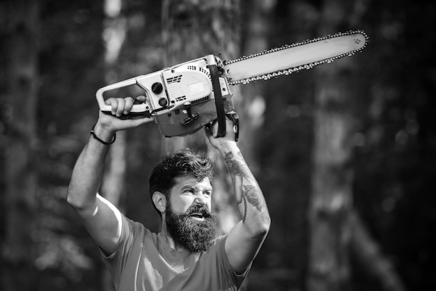 Lenhador na floresta com motosserra machado jovem bonito com machado perto da floresta motosserra deforesta