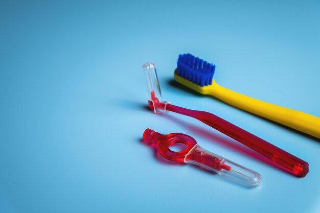 Foto lente de dientes de color brillante con cepillo ortodóncico interdental sobre fondo azul con espacio para copiar