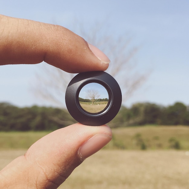 Foto lente de mano recortada delante del campo