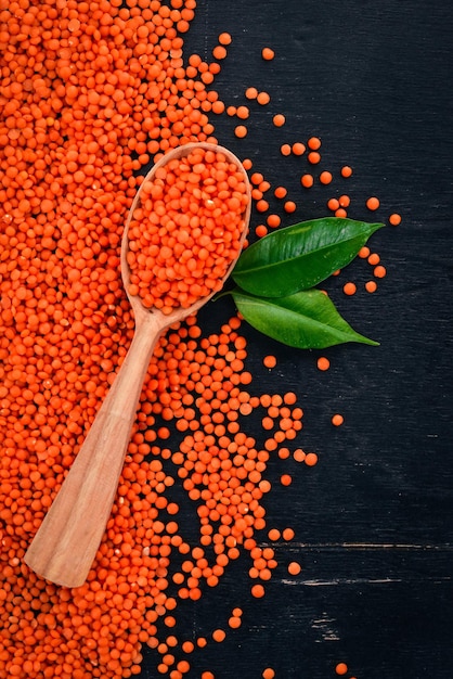 Lentejas naranjas en una cuchara Sobre un fondo de madera Vista superior Espacio de copia