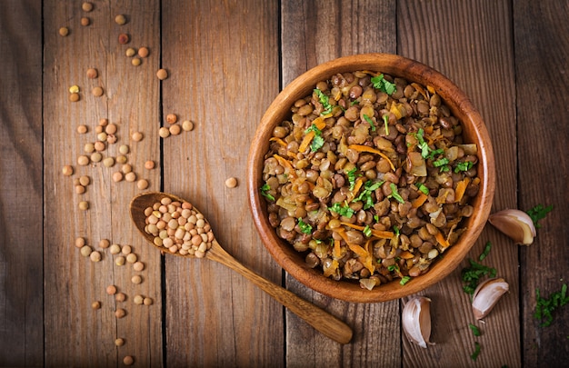 Lentejas con zanahoria y cebolla en un tazón de madera. Estilo de vida saludable. Menú de dieta