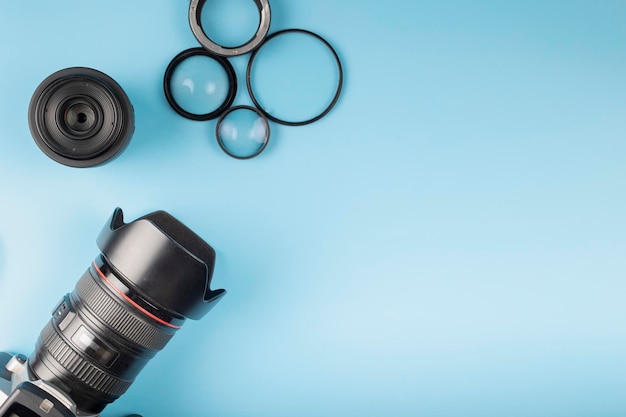 Lentes de câmeras fotográficas e equipamentos de fotógrafos sobre um fundo azul com espaço para texto