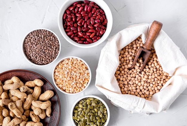 Lentilhas, amendoins, sementes de abóbora, grão de bico e feijão em taças.