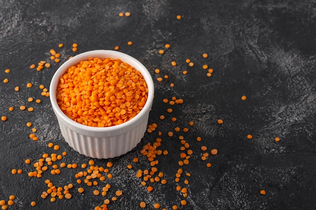 Lentilhas laranja em um copo branco sobre um fundo preto