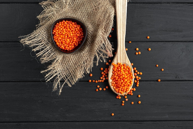 Lentilhas vermelhas em um fundo rústico de madeira escura lentilhas de cereais em uma colher de madeira alimento antigo d