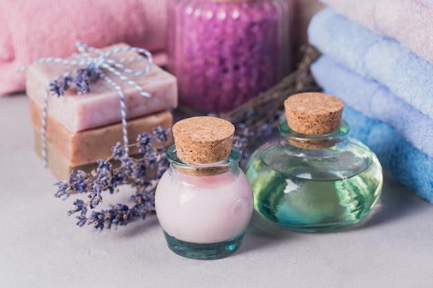 Óleo cosmético natural, creme, sal marinho e sabonete artesanal natural com lavanda sobre fundo claro. Cuidados com a pele saudável. Conceito de aromaterapia, spa e bem-estar