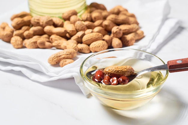 Óleo de amendoim em um jarro de vidro e amendoim descascado cru para aromaterapia medicinal e usos culinários