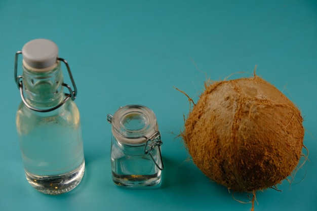Óleo de coco virgem ou VCO em uma garrafa na mesa turquesa coco casca de coco prensado a frio