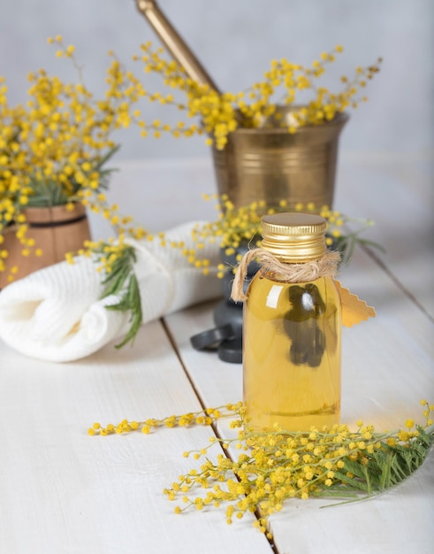 Óleo de massagem de flores de mimosa em frasco de vidro. Fechar-se