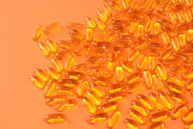 Óleo de peixe, Omega-3. Vitaminas saudáveis, medicamentos em cápsulas transparentes moles em um fundo laranja