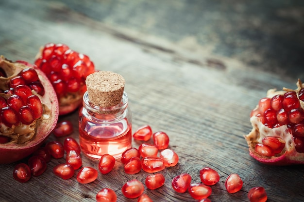 Óleo de romã em garrafa e fruta granada com sementes na mesa Foco seletivo
