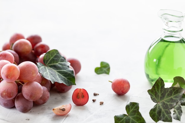 Óleo de semente de uva em uma garrafa de vidro com um cacho de uvas