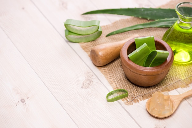 Óleo essencial de aloe vera e folhas de aloe vera em um fundo branco.