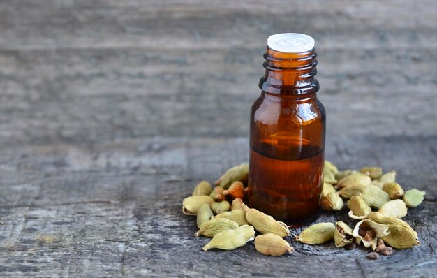 Óleo essencial de cardamomo em um frasco de vidro na mesa de madeira velha. Extrato de cardamomo de Elettaria.