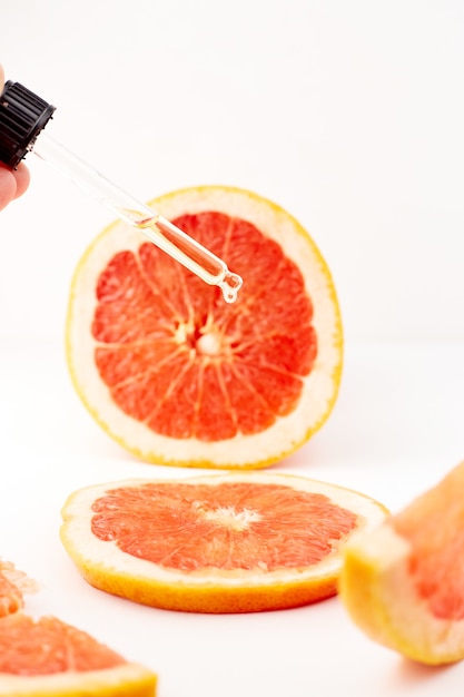 Óleo essencial de citrino ou toranja em frasco de vidro com toranja fresca na superfície branca