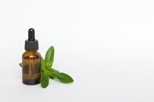 Óleo essencial de hortelã natural em uma garrafa de vidro cosméticos orgânicos com extratos de ervas de hortelã em fundo colorido
