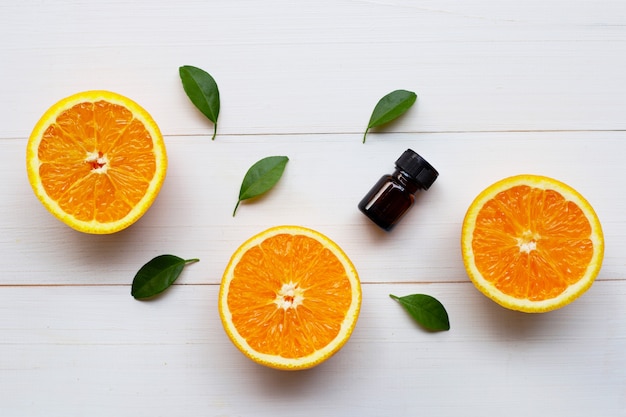 Óleo essencial de laranja com frutas cítricas laranja e folhas verdes em branco de madeira