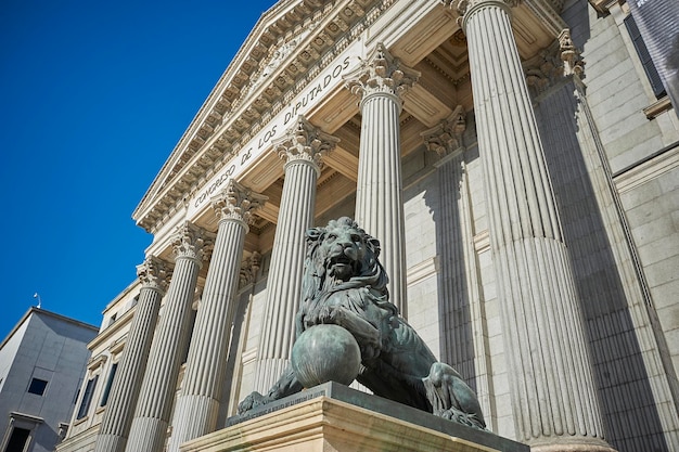 Foto leones de bronce en la famosa fachada del edificio del parlamento español, madrid (españa)