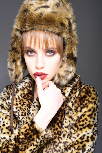 Leopard-Pelz auf stilvolle Mädchen Look von Mode-Modell mit schlechtem Geschmack Pelzmantel-Boutique mit natürlichen und künstlichen Materialien Frau im Leoparden-Pelz-Mantel, isoliert auf weiss Wintermode und Schönheit
