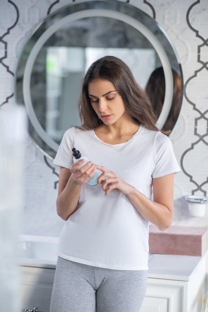 Ler um guia do usuário. Uma mulher lendo o rótulo do novo spray de cabelo