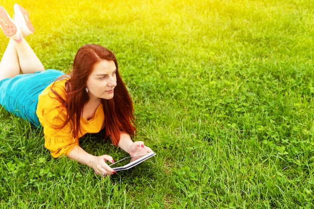 Lernkonzept Junge Frau, die das Legen der Tablette im Freien auf Gras verwendet