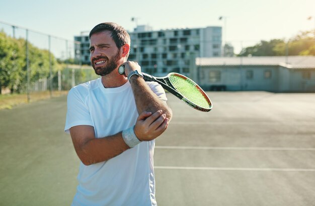 Lesão de tênis e dor nas articulações pelo homem na quadra para treinamento físico ou treino com problema Acidente esportivo e jogador do sexo masculino com artrite e osteoporose no braço lesionado e músculo ou fibromialgia