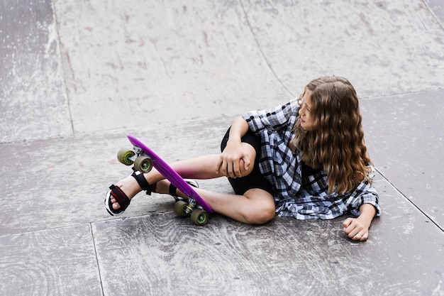 Lesão na perna e no joelho na placa de centavo Traumatologia infantil Menina caindo do skate e se machucando e sentindo dor