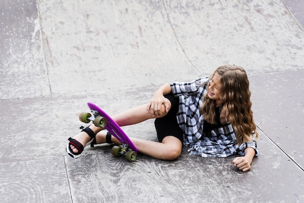 Foto lesão na perna e no joelho na placa de centavo traumatologia infantil menina caindo do skate e se machucando e sentindo dor