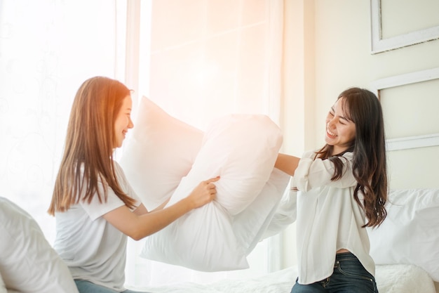 Lesbische Frauen bei Kissenschlachten im Schlafzimmer.