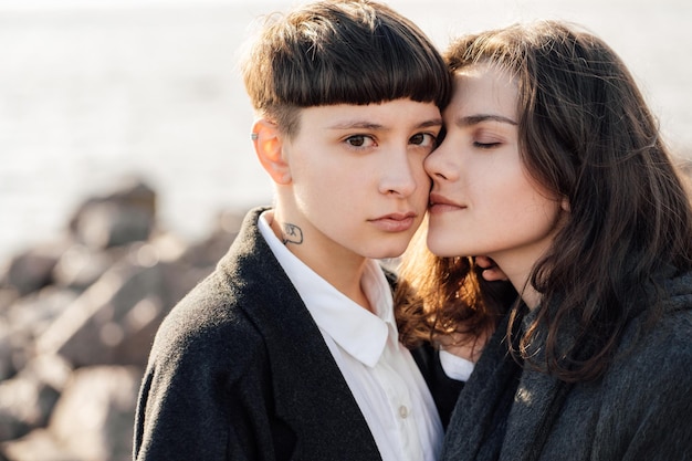 Lesbische Frauen umarmen sich, während sie auf einem Felsen gegen das Meer stehen