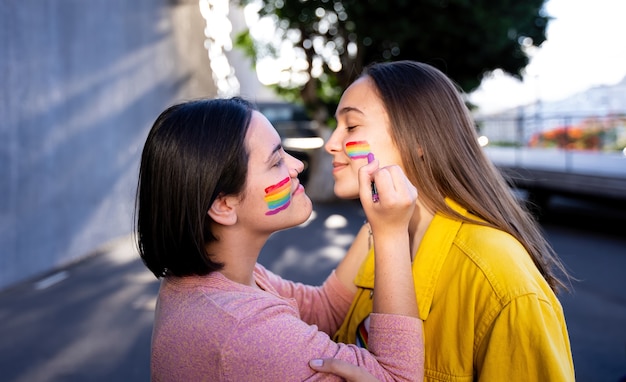 lesbische Mädchen, die Spaß daran haben, sich selbst zu malen und mit der LGtb-Flagge am Stolztag LGtb-Konzept