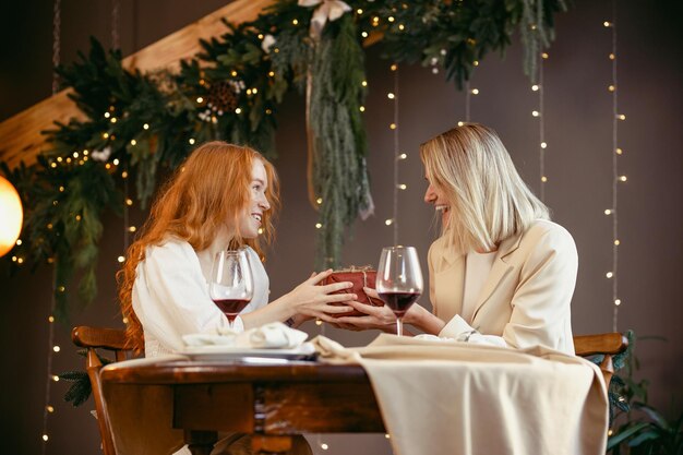 Lesbisches Paar beim Abendessen in einem Restaurant. Mädchen gibt ihrem Schatz ein Geschenk