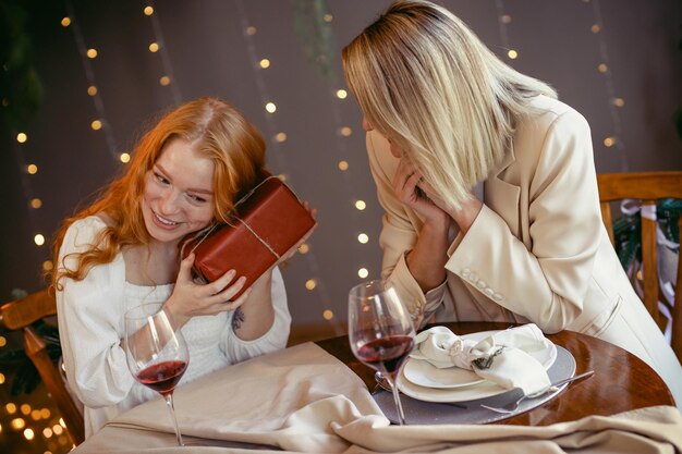 Lesbisches Paar beim Abendessen in einem Restaurant. Mädchen gibt ihrem Schatz ein Geschenk