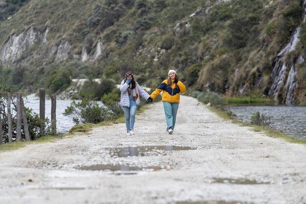 Lesbisches Paar geht zu Fuß und hält Händchen für einen Weg neben einem See