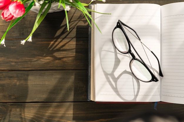 Lesebrille auf offenes Buch über Holztisch