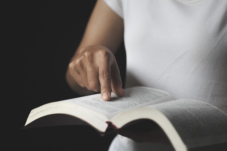 Foto lesen mit einer hand, die auf die schriften weist, treue und christliche frau, die betet