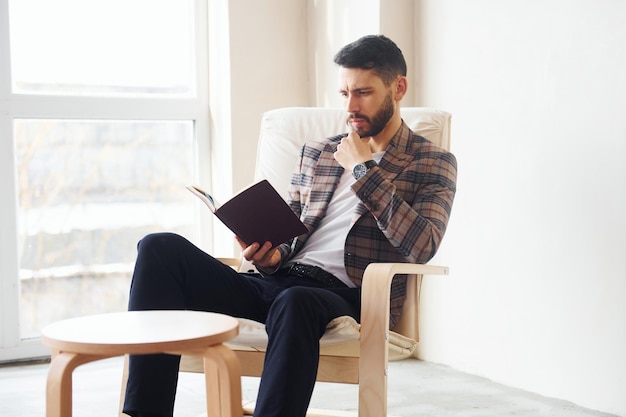 Lesen Sie das Buch Junger stilvoller Geschäftsmann im Anzug im Inneren Konzept des Erfolgs