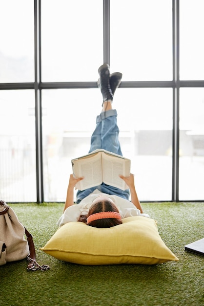 Foto lesen von bildung und buch mit einer studentin entspannen sie sich auf dem boden in einem pausen- oder studienraum auf dem universitätscampus hochschulstipendium und lernen mit einer frau, die für wachstum und entwicklung studiert