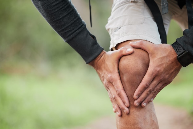 Lesión por dolor de rodilla y mano de persona al aire libre con ejercicio físico y accidente de entrenamiento por caminata Masaje de piernas de corredor y falla por caminata en el bosque en un sendero con tensión muscular y emergencia