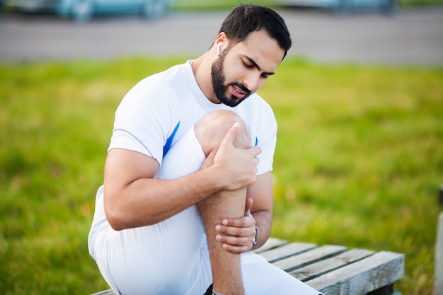 Foto lesión en una pierna. atleta masculino sufriendo de dolor en la pierna mientras hace ejercicio al aire libre