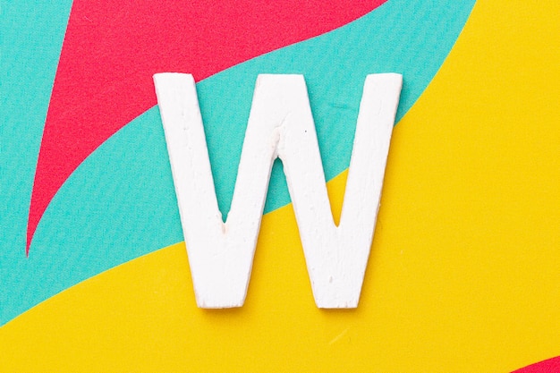 Letra W do alfabeto na vista superior do plano de fundo colorido