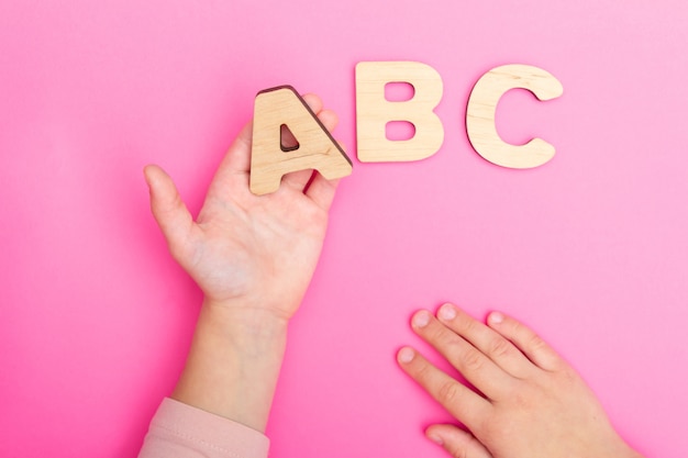 Foto letras abc nas mãos da criança em fundo rosa