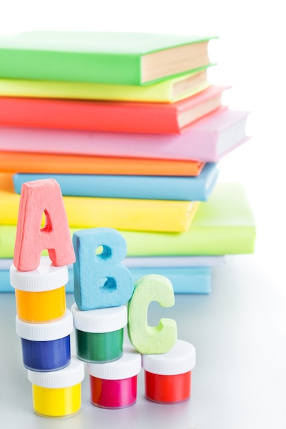 Letras abc y pila de libros sobre un fondo blanco.