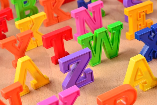 Foto letras del alfabeto de colores de plástico de cerca sobre un fondo de madera