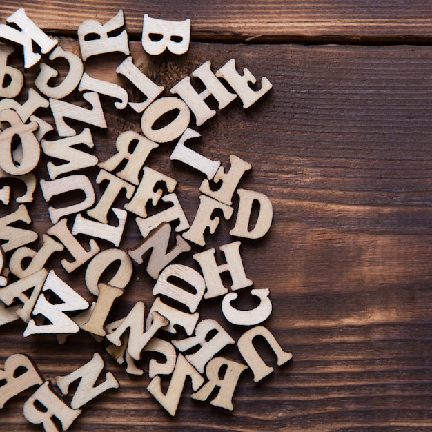 Letras del alfabeto inglés sobre un fondo de madera oscura. El concepto de educación, juegos de palabras, costura. Espacio para texto