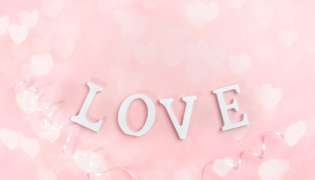 Letras blancas AMOR en rosa pastel con corazones de luces bokeh Fondo festivo Vista superior endecha plana