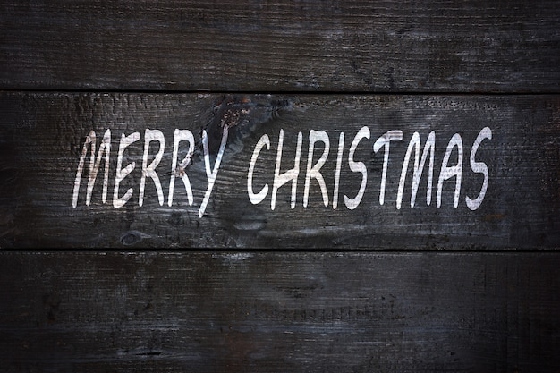 Letras blancas feliz navidad sobre fondo de madera negra