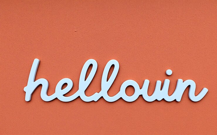 Foto letras blancas en una pared naranja un saludo lúdico y festivo de halloween