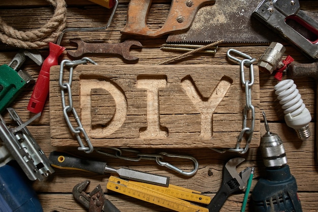 Foto letras de bricolaje en una tabla de madera en el fondo de herramientas de trabajo