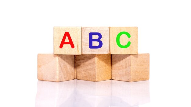 Letras de colores ABC sobre bloques de madera, apilados horizontalmente.